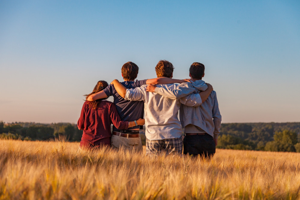 Four people hugging in a field